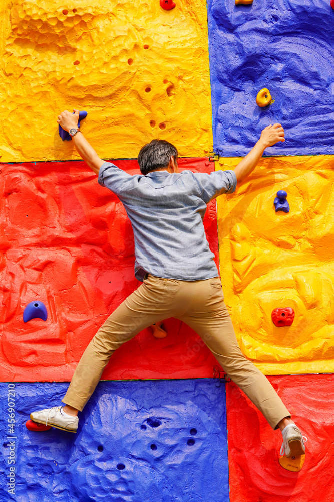 Obraz premium Man climbing wall without grips. Businessman climb on colourful wall