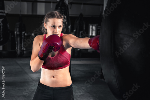 Attractive young woman boxing at the gym. Female boxer preparing for training in boxing club © andyborodaty