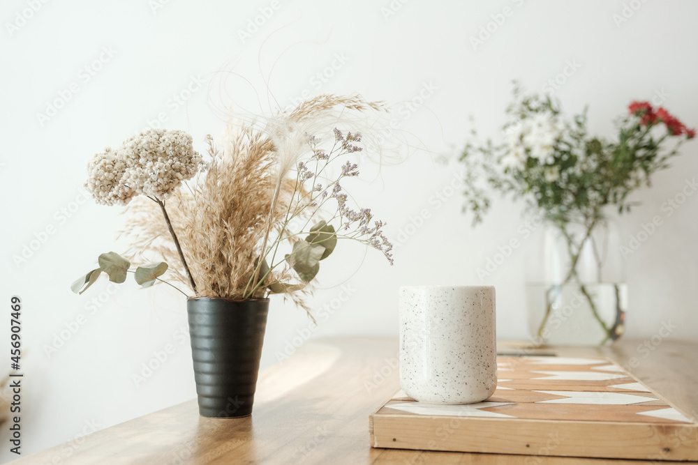 Dried grass in vases stands on a white table Dried grass in vases stands on a white table