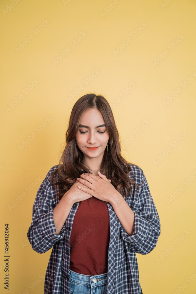 a beautiful woman feeling calm with her eyes closed with hand gesture holding chest while standing with copyspace a beautiful woman feeling calm with her eyes closed with hand gesture holding chest while standing with copyspace