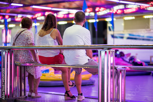 Una familia espera frente a los coches de choque en el recinto ferial. Diversión en la feria, parque de atracciones. Autos chocadores. photo