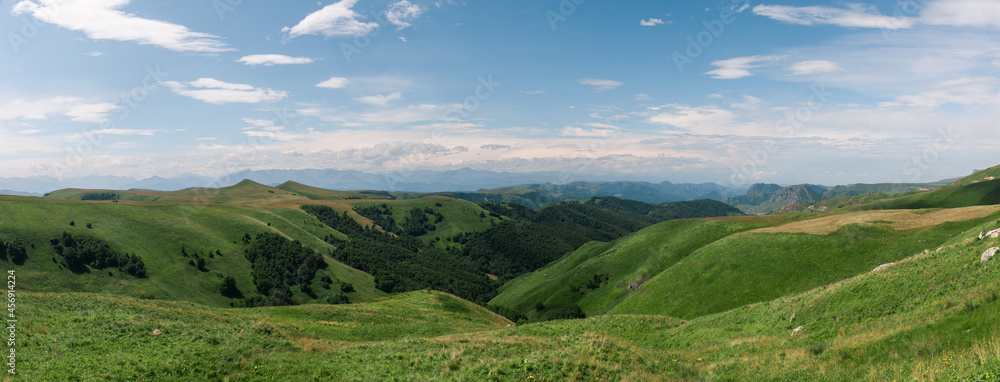 Obraz premium Panoramic view of green hills and blue mountains