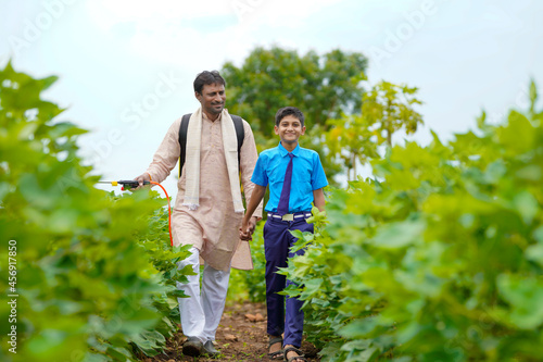 Young indian farmer with his son at green agriculture field.