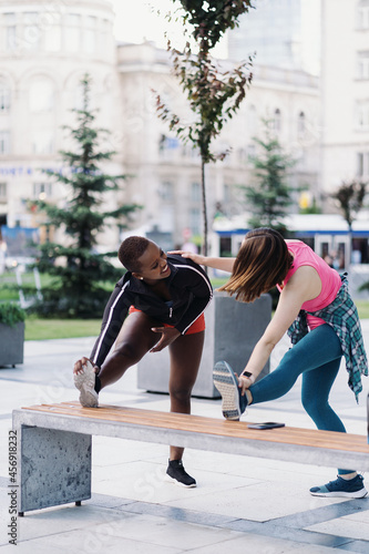 Two fit diverse young woman working out together in city square doing stretching exercise and hand extensions © arthurhidden