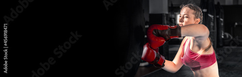 Attractive young woman boxing at the gym. Female boxer preparing for training in boxing club © andyborodaty