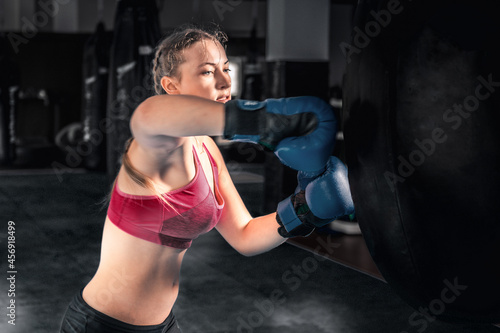 Attractive young woman boxing at the gym. Female boxer preparing for training in boxing club