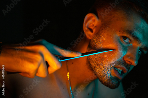 aggressive portrait of a guy with a knife in neon light