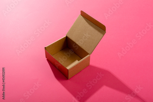 Composition of open empty cardboard gift box on pink background