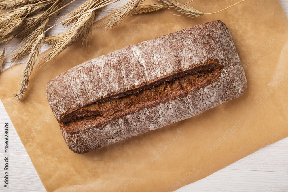 Overhead view of homemade rye ciabatta bread and spikelets of rye on a light wooden table. Overhead view of homemade rye ciabatta bread and spikelets of rye on a light wooden table.