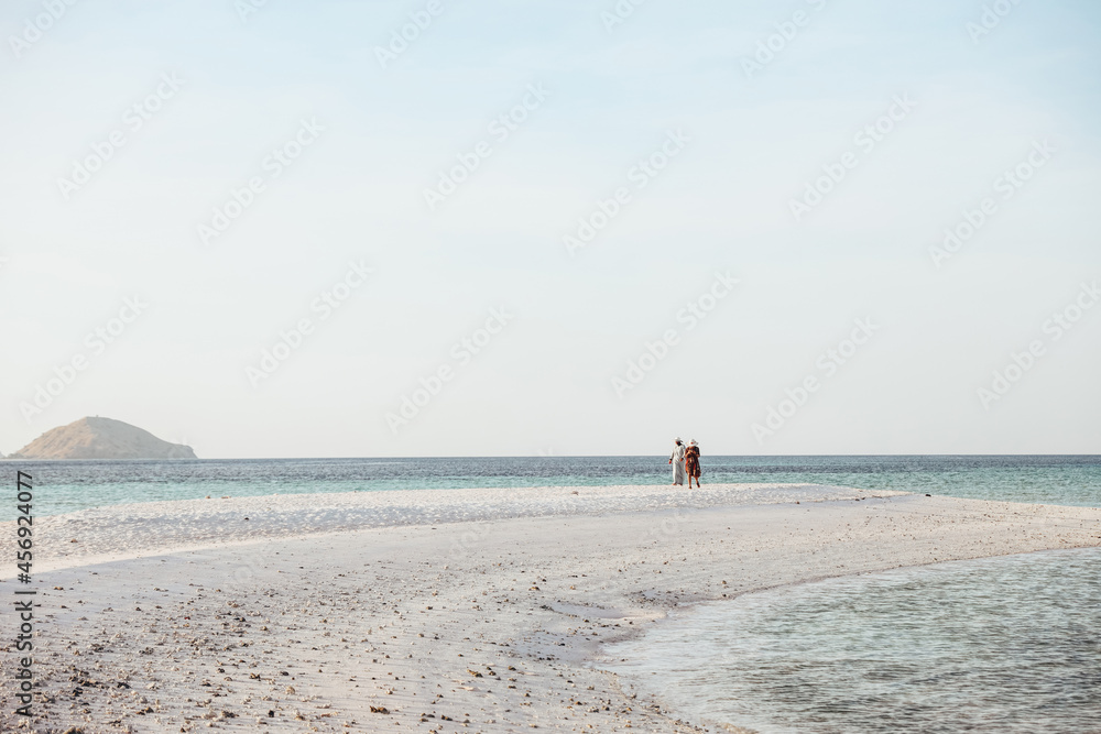 Two women tourist walking on the white sand beach
