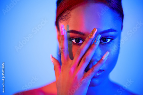 Fotografie Beautiful afro woman clothing face with hand, looking through fingers at camera