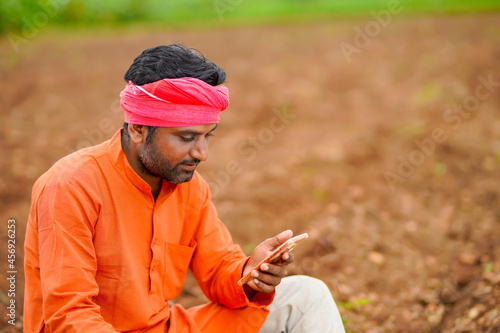 technology concept : Young indian farmer using smartphone at field