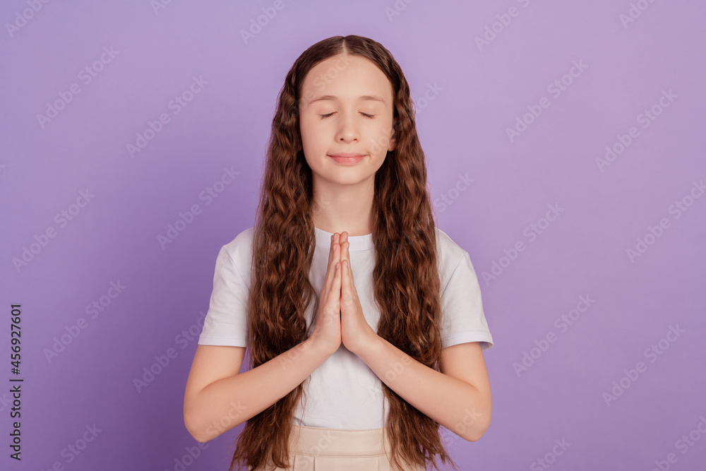 Portrait of peaceful lovely sweet small girl hold palms together yoga lesson on purple background Portrait of peaceful lovely sweet small girl hold palms together yoga lesson on purple background