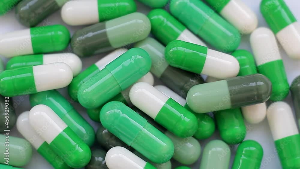 Seamless loop, backdrop, background texture, intro. Slow rotation of white and green capsules, tablet flat lay, close-up. Seamless loop, backdrop, background texture, intro. Slow rotation of white and green capsules, tablet flat lay, close-up.