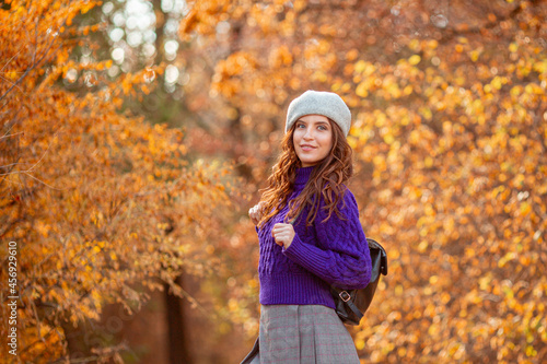 a young woman in an autumn park in a purple sweater