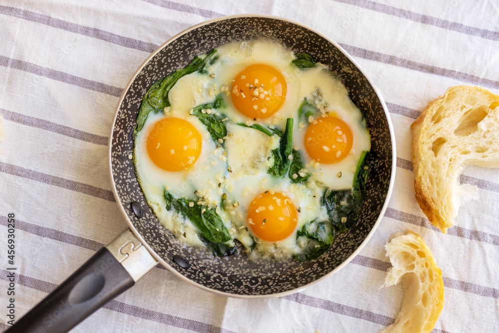 Top views to fried eggs with spinach, cheese and hemp seeds in skillet. Healthy breakfast or brunch. Top views to fried eggs with spinach, cheese and hemp seeds in skillet. Healthy breakfast or brunch.