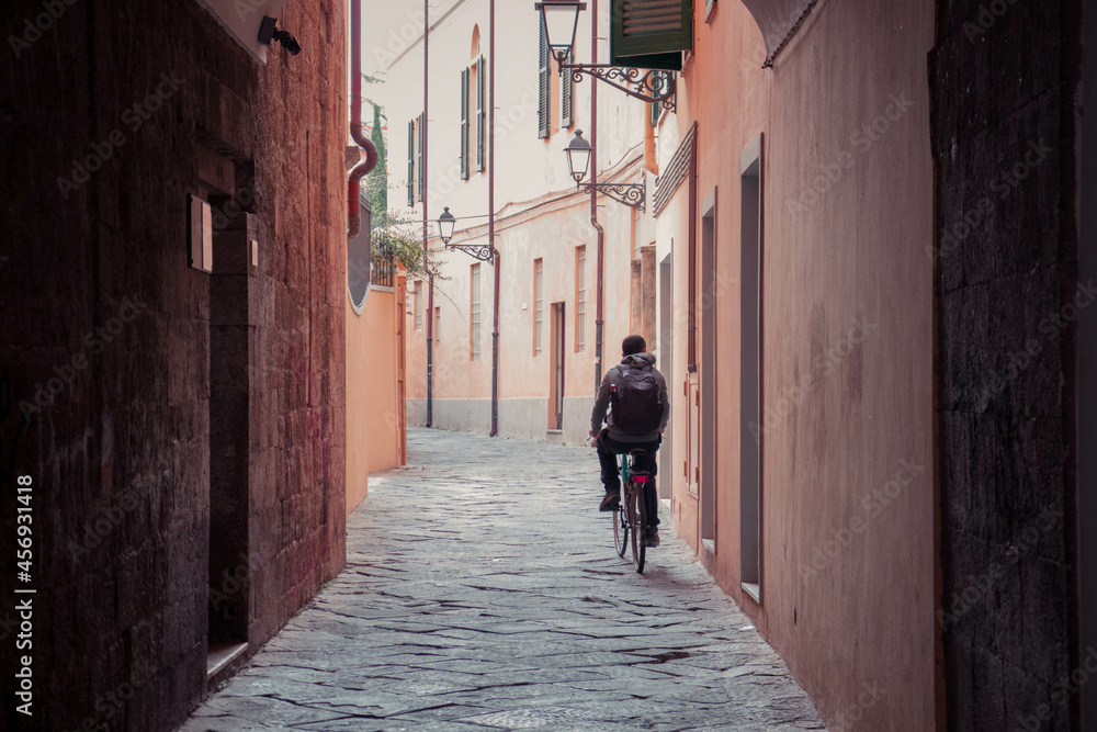 A man driving a bike down a Italian alley from the back