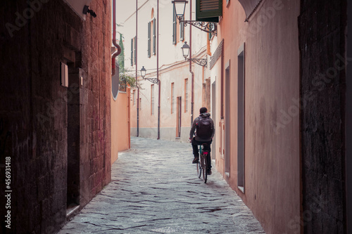 A man driving a bike down a Italian alley from the back