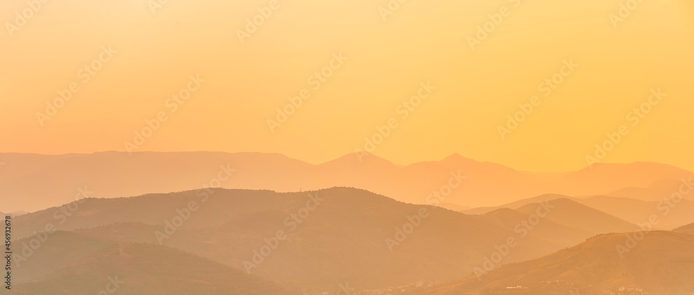 Silhouettes of mountains at dawn or sunset. Beautiful natural orange landscape