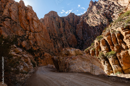 Gravel road of Swartberg pass winding through contorted rock formations photo