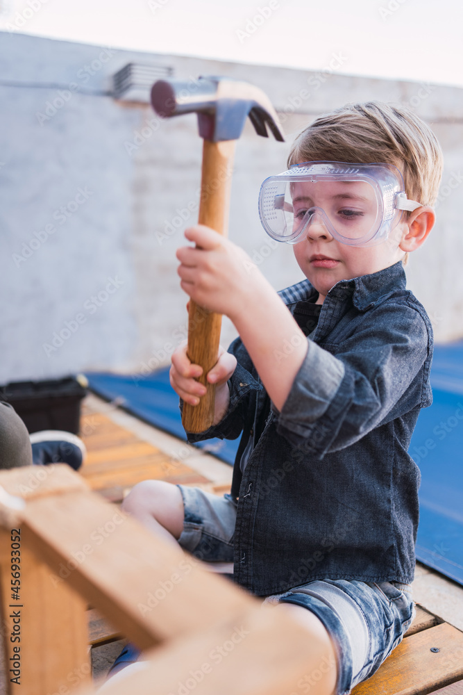 Boy in protective glasses with hammer in daytime Boy in protective glasses with hammer in daytime