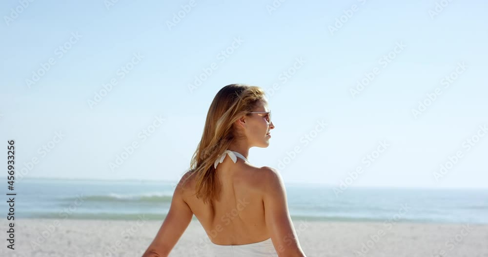 Gorgeous woman tying up hair on beach wearing stylish designer one piece swimsuit has slim athletic figure Gorgeous woman tying up hair on beach wearing stylish designer one piece swimsuit has slim athletic figure