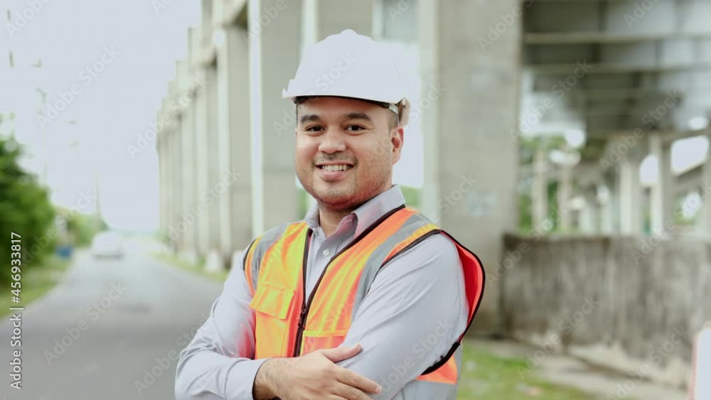 Asian engineer handsome man or architect looking construction with white safety helmet in construction site. Standing at highway concrete road site. Asian engineer handsome man or architect looking construction with white safety helmet in construction site. Standing at highway concrete road site.