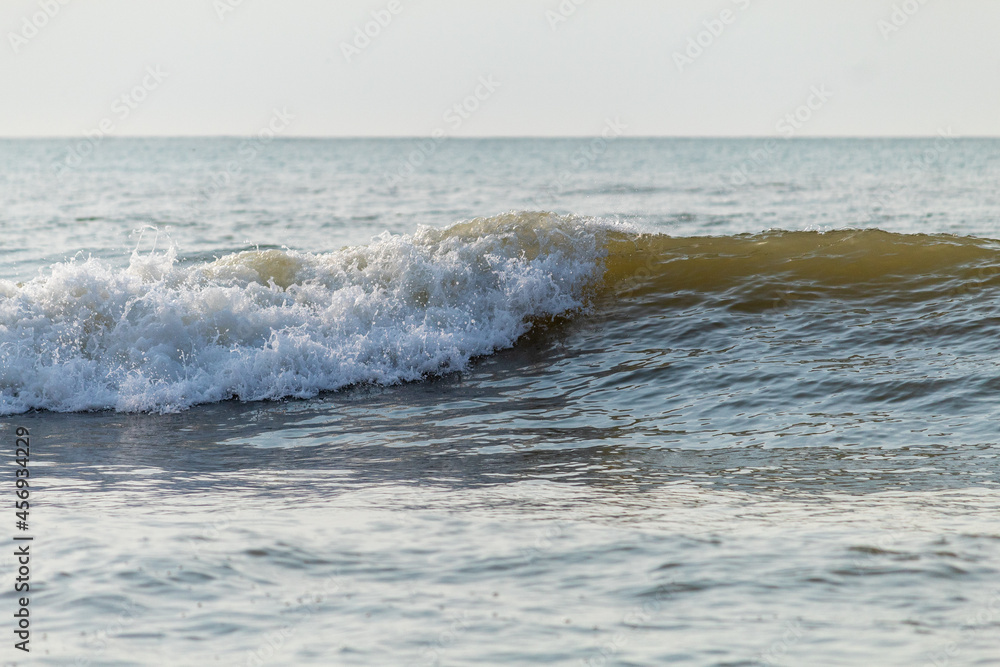 Fototapeta premium ONDA QUEBRANDO NO MAR, REFLETINDO O NASCER DO SOL.