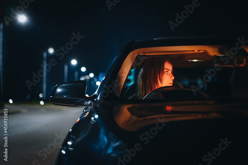 Woman driving car on road at night