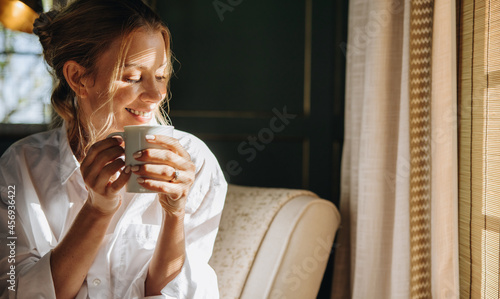 Smiling young woman enjoying a cup of coffee in a hotel photo
