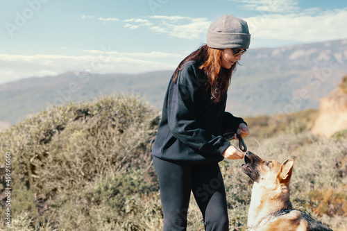 Young woman offering her German Shepherd dog a treat during a training outdoors