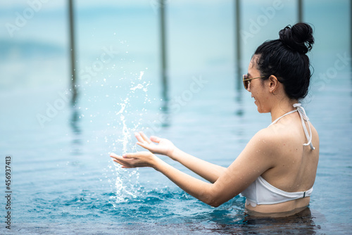 Asian woman lifestyle with summer water, young female girl wearing swim ware to swimming in water pool, vacation time in holiday to relax and happy with healthy enjoyment leisure
