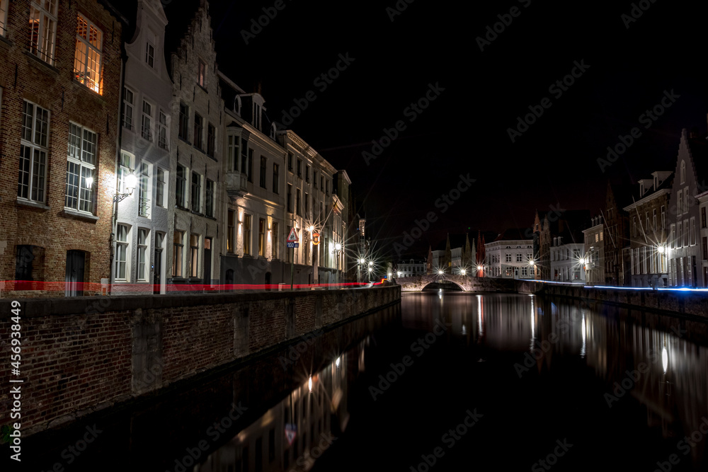Long exposure night photograph of a canal with car light trails in the old center of Bruges, Belgium