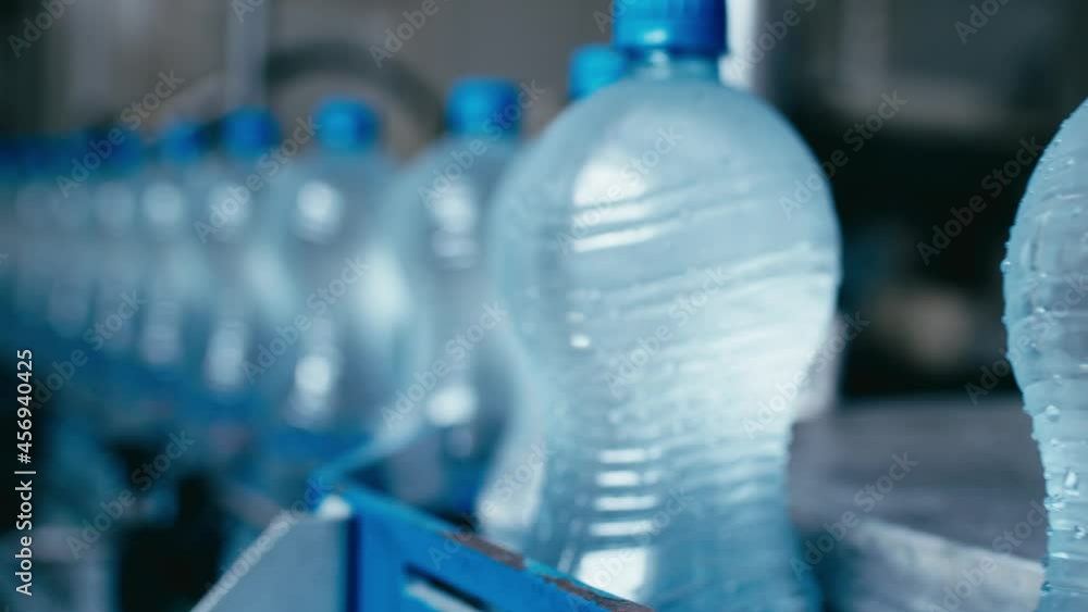 Water bottles moving on automatic conveyor line in water production factory Water bottles moving on automatic conveyor line in water production factory