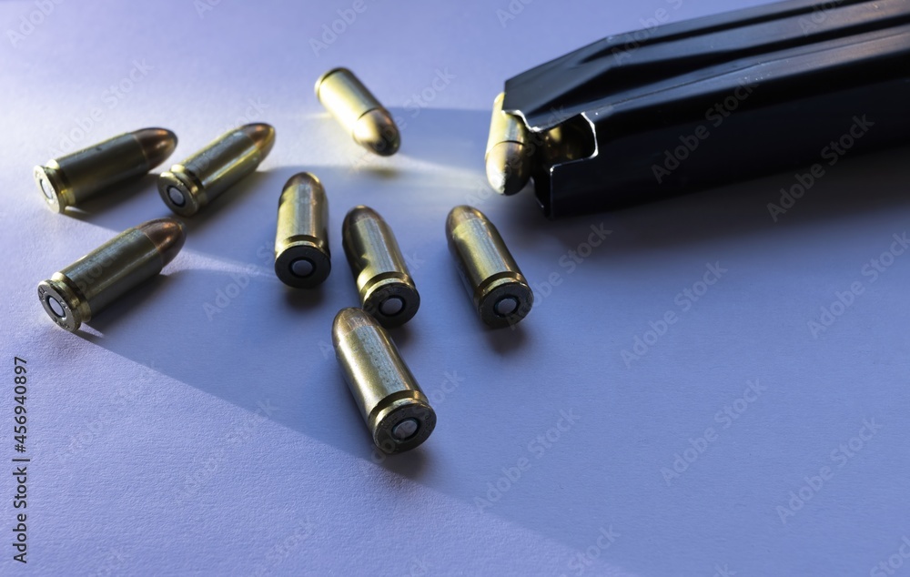 9mm caliber parabellum bullets isolated with grazing light next to a magazine of pistol ammunition 9mm caliber parabellum bullets isolated with grazing light next to a magazine of pistol ammunition