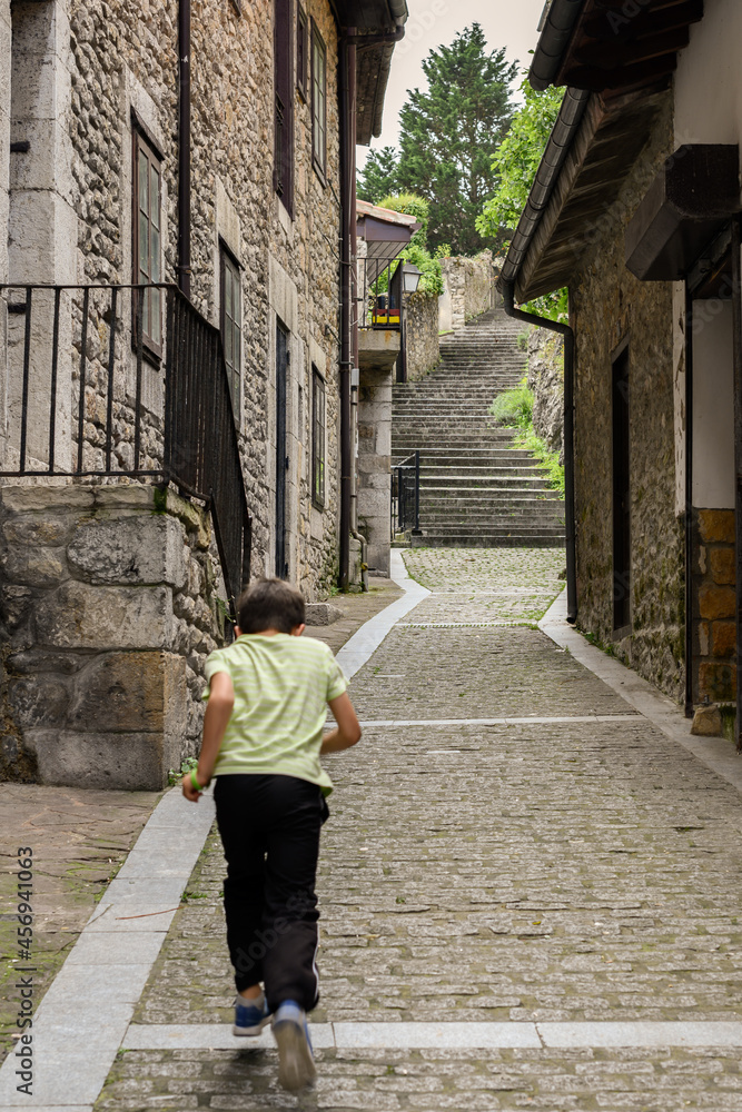 A boy runs along a stone street in a rural village.
