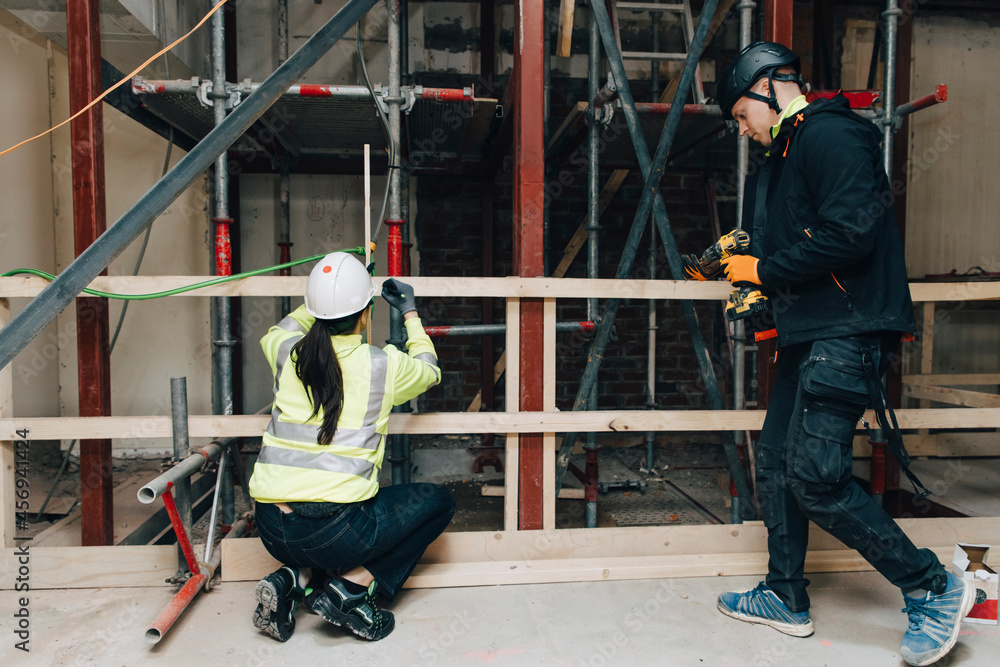 Full length of male and female worker together at construction site Full length of male and female worker together at construction site