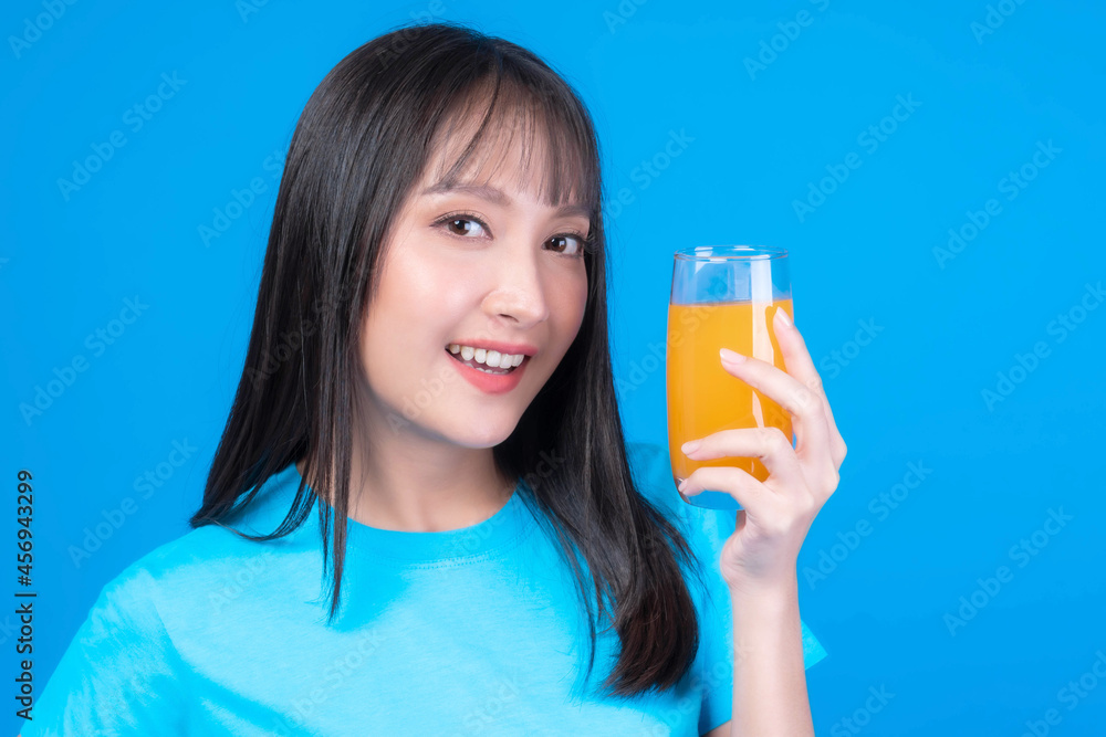 Beautiful beauty Asian woman cute girl with bangs hair style in blue t shirt feel happy drinking orange juice for good health on blue background - lifestyle beauty woman healthy concept Beautiful beauty Asian woman cute girl with bangs hair style in blue t shirt feel happy drinking orange juice for good health on blue background - lifestyle beauty woman healthy concept