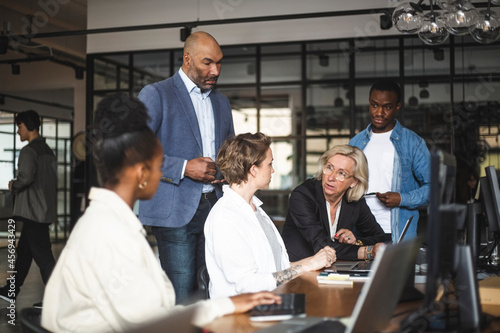 Female investors discussing with computer programmer at creative office