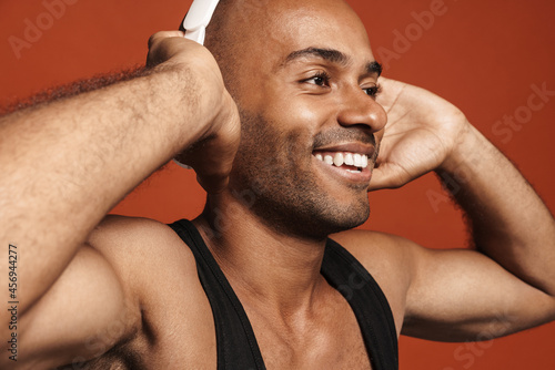 Black bold man smiling while listening music with headphones