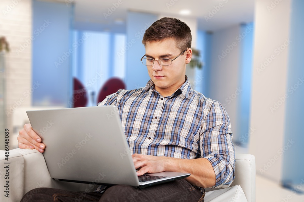 Smiling young adult freelance business man using laptop