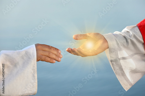 Jesus Christ and man near water outdoors, closeup. Miraculous light in hand