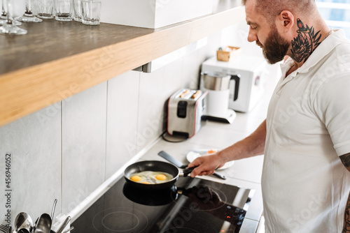 White man with beard cooking lunch in kitchen at home