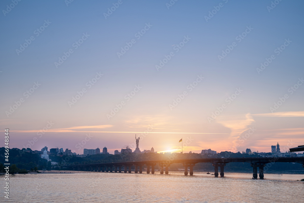 Beautiful view to the right side of Kyiv (Kiev) Ukraine. River Dnieper, Paton Bridge, Kyiv Pechersk Lavra and Motherland Monument main popular sightseeing places. Summer Sunset romantic soft light