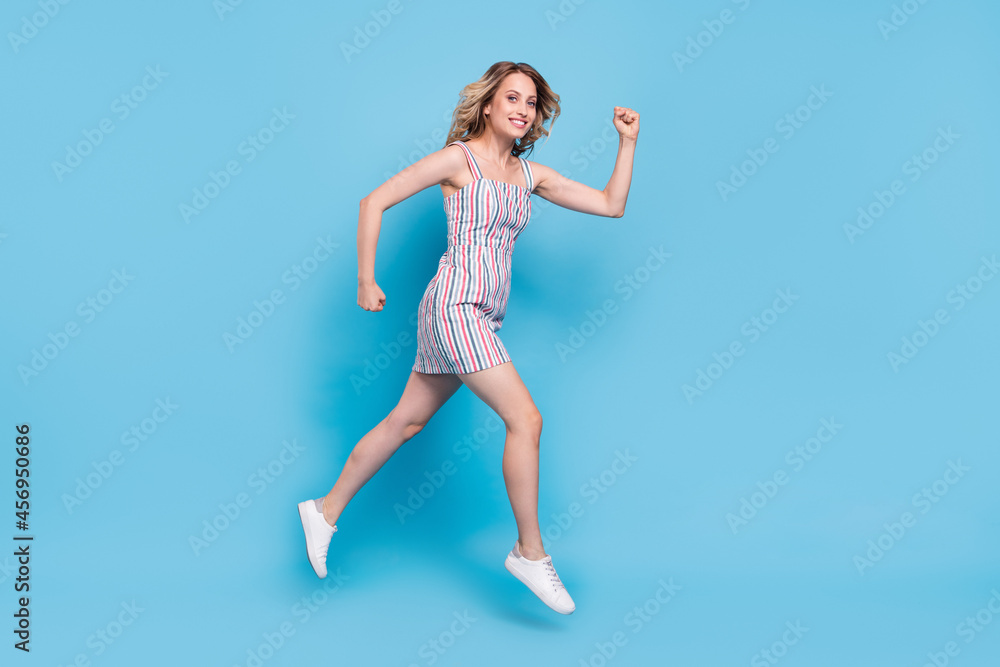 Full length body size photo woman running jumping high wearing stylish outfit isolated pastel blue color background Full length body size photo woman running jumping high wearing stylish outfit isolated pastel blue color background