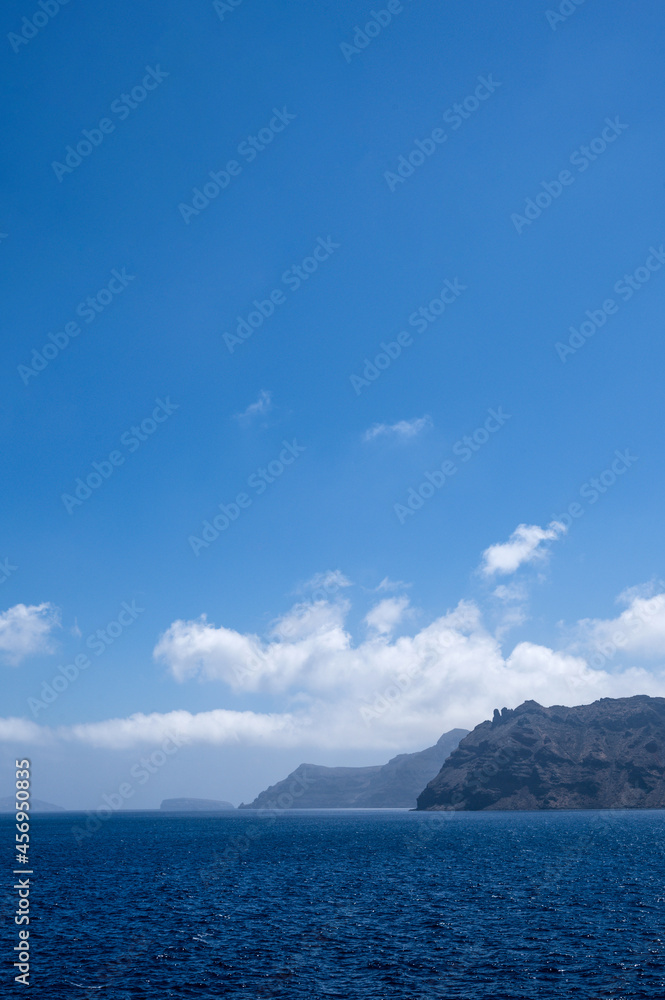 Scenic landscape of Aegean sea at sunny summer day. Santorini island. Silhouettes of islands in mist.