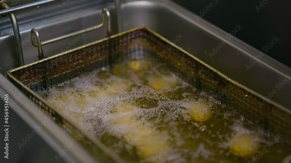 Fries in the deep fryer. Chef cooking in modern kitchen of restaurant Fries in the deep fryer. Chef cooking in modern kitchen of restaurant
