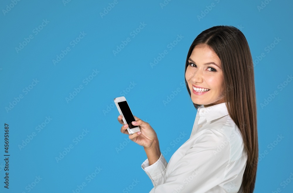 Young lady using a phone with positive expression, smiles broadly Young lady using a phone with positive expression, smiles broadly