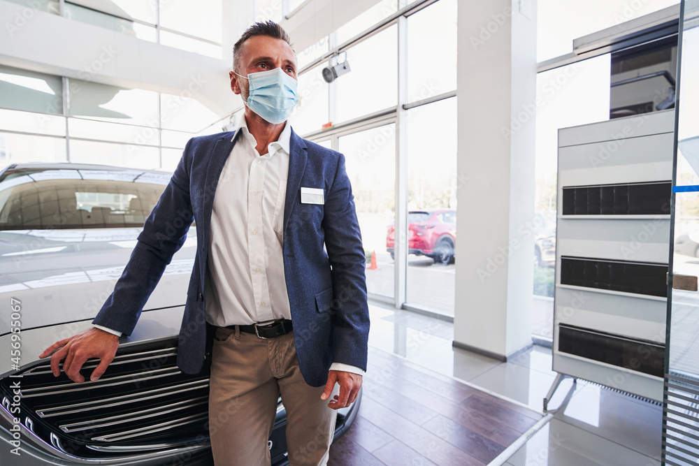 Salesman at his workplace in modern car dealership Salesman at his workplace in modern car dealership