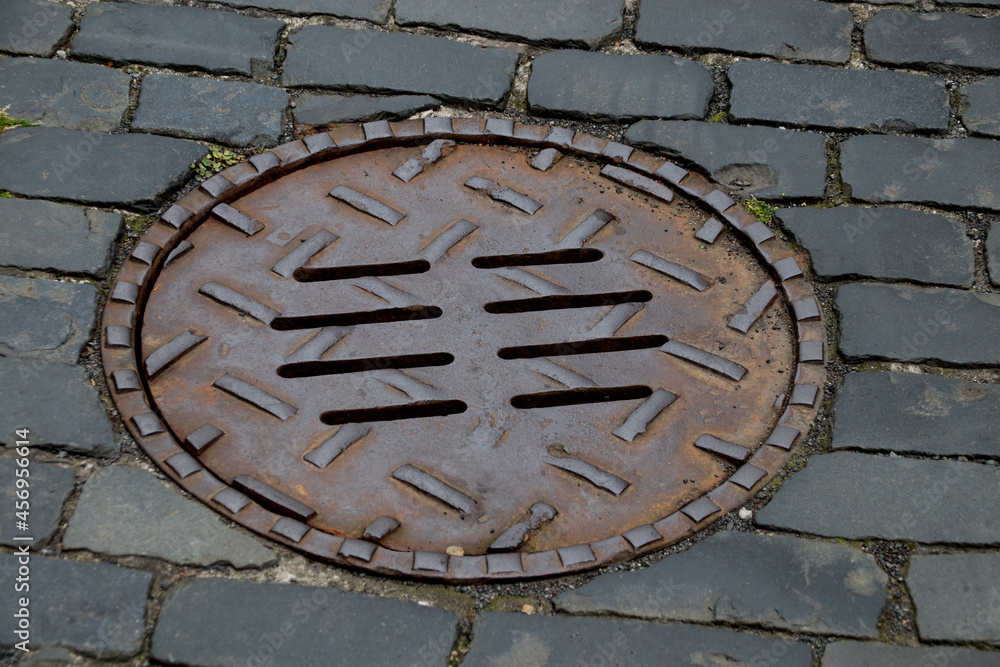 Manhole Cover on an Old Cobbled Village Street Manhole Cover on an Old Cobbled Village Street